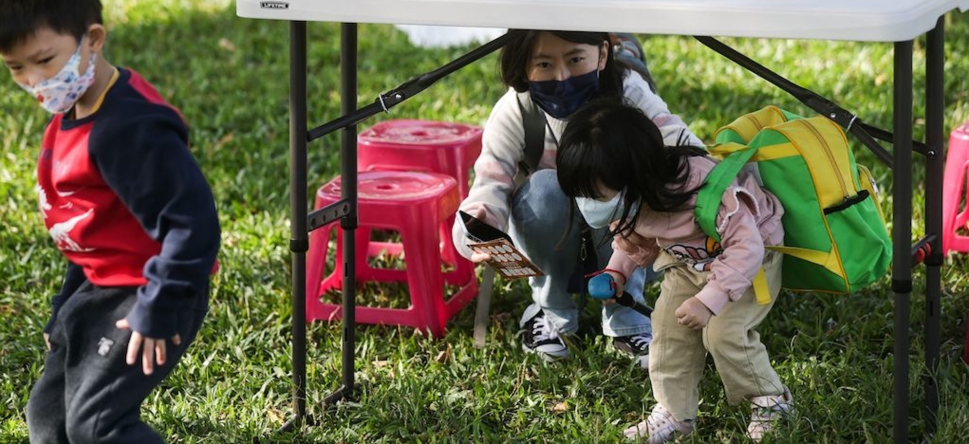 Children practice carrying first aid kits while negotiating obstacles on roads during an event held by Taiwanese civil defense organization Kuma Academy, in New Taipei City on November 18, 2023, to raise awareness of natural disaster and war preparedness. 