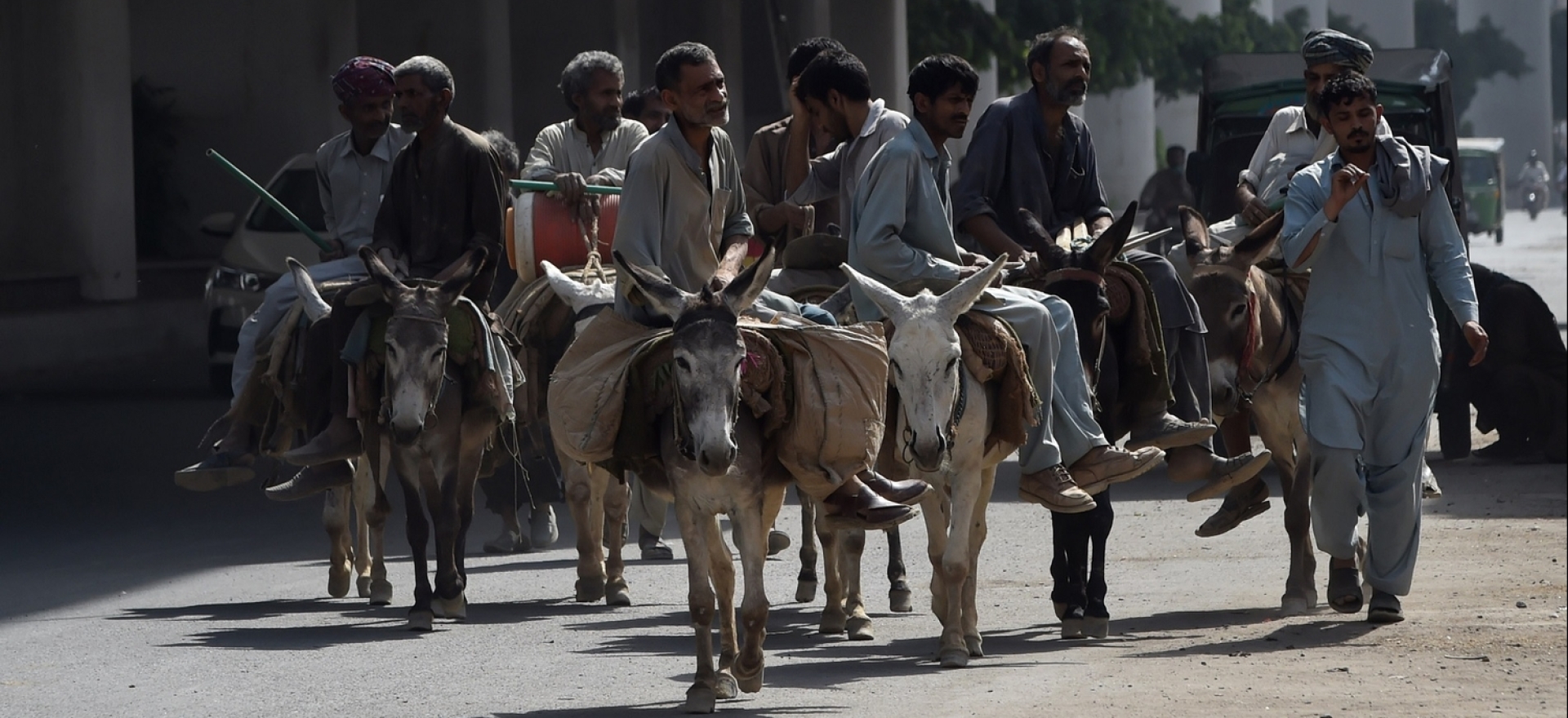   Men ride donkeys on a street during International Labor Day, in Lahore, Pakistan, May 1, 2020.