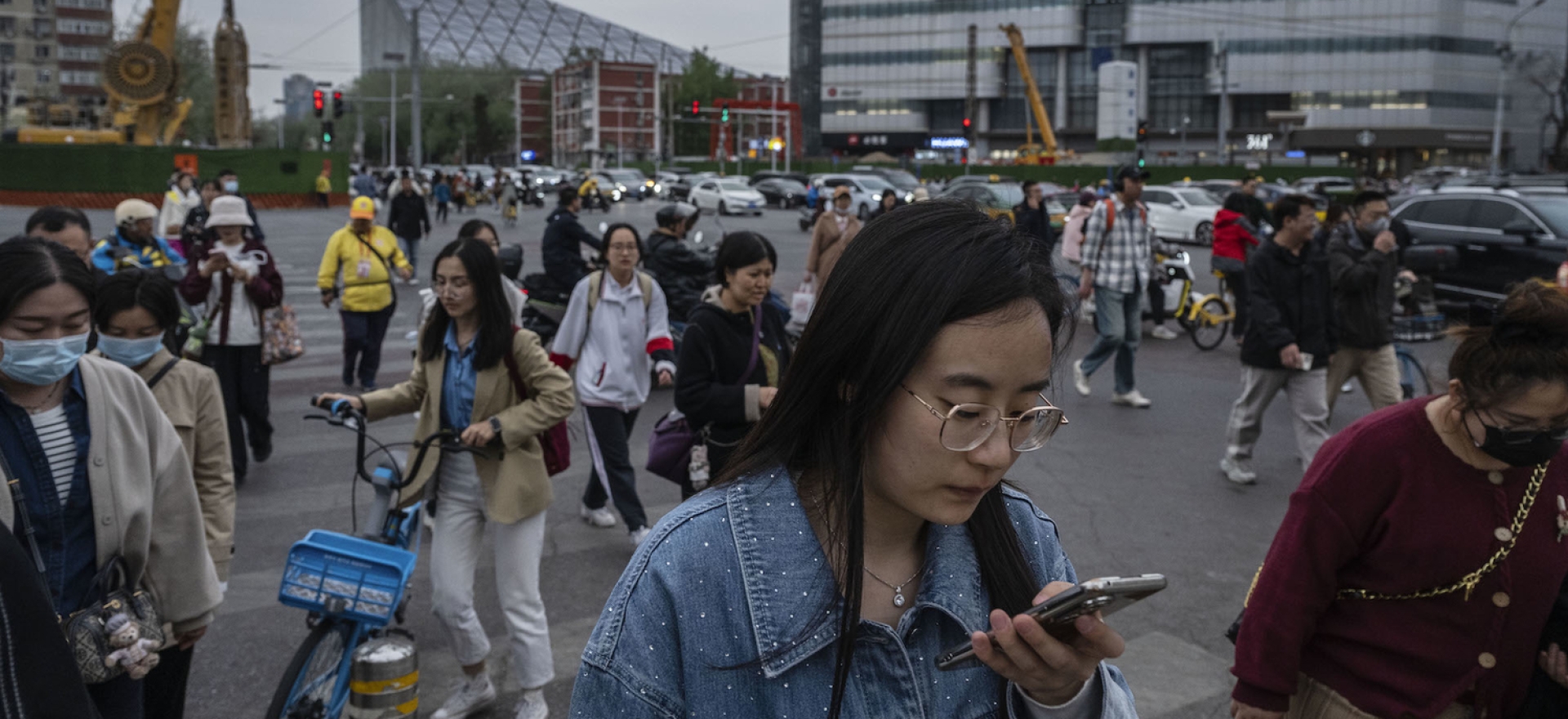   People cross at a traffic light as a screen shows an ad for Apple’s iPhone 16, in Beijing, April 8, 2025. China announced plans Friday to impose a 34 percent tariff on imports of all U.S. products starting April 10, in retaliation following U.S. President Donald Trump’s “Liberation Day” tariff announcement.
