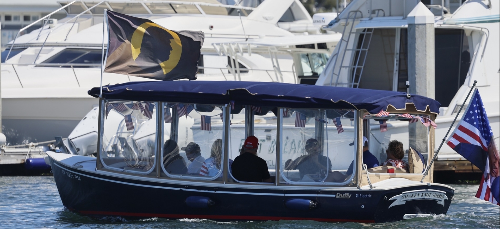 A boat flies a flag bearing an image of Donald Trump, during a demonstration of support for the then former president and presidential candidate in Huntington Harbor, Huntington Beach, July 27, 2024.