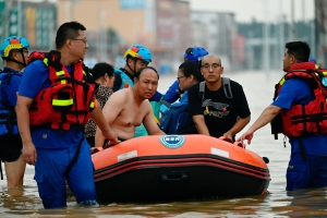 Rescue team personnel wade in a flooded road as they evacuate residents following heavy rains in Zhuozhou, in northern China's Hebei province on August 2, 2023.