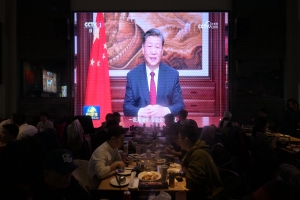 People have their dinner at a restaurant as a screen broadcasts China's President Xi Jinping while delivering his New Year's speech in Beijing on December 31, 2023.