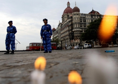 Indian paramilitary forces stand guard as candles placed by people in memory of those killed by militants burn in front of the Taj Mahal hotel in Mumbai on November 30, 2008. (Sajjad Hussain/AFP/Getty Images)  