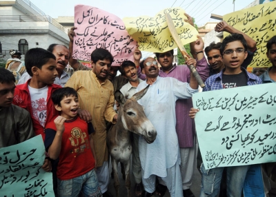 Pakistani cricket fans pose with a donkey as they shout slogans against national cricket team players involved in a match fixing scandal during a protest in Lahore on August 30, 2010. (STR/AFP/Getty Images)