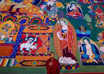 A Bhutanese monk stands in front of a large Thangkha painting at the Dratshang Kuenra Tashichho Dzong on November 6, 2008 in Thimphu, Bhutan. (Paula Bronstein/Getty Images)