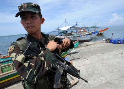 A Philippine soldier stands guard next to fishing boats at a pier in Masinloc town, Zambales province, 140 miles from Scarborough Shoal, on May 18, 2012. (Ted Aljibe/AFP/GettyImages)