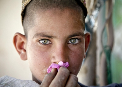 A young Afghan boy smells a flower in the Oshay Bazaar, Uruzgan province, Afghanistan, April 26, 2011. (DVIDSHUB/Flickr)