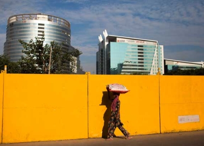 A pedestrian walks past a construction site near corporate offices in Gurgaon