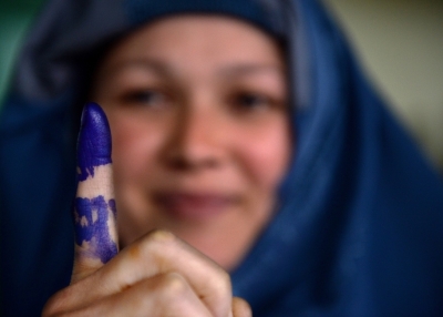 An Afghan voter shows her inked finger after she cast her ballot on 5 April 2014