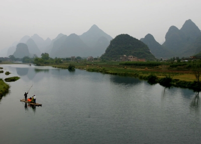 A villager rows a bamboo raft carrying tourists for sightseeing on the Lijiang River in Yangshuo County of Guilin, Guangxi Zhuang Autonomous Region, South China. (Photo by China Photos/Getty Images)