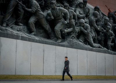 A man rushes past a war memorial statute in Pyongyang, North Korea on April 12, 2015. (ze Dirk/Flickr)