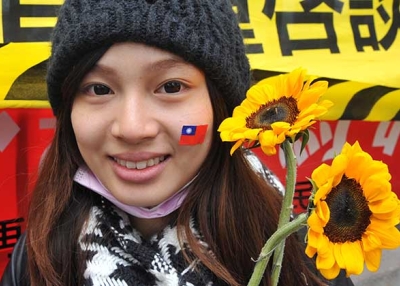 An activist holds sunflowers and wears a sticker of Taiwan's national flag on her face in support of student protesters occupying the parliament building in Taipei on March 21, 2014. (Mandy Cheng/AFP/Getty) 