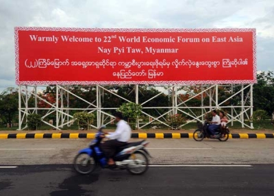 Locals ride motorcycles past a billboard for the 22nd World Economic Forum on East Asia, held this year in Myanmar's capital city of Naypyidaw, on June 3, 2013. (Soe Than WIN/AFP/Getty Images)