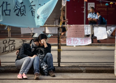 Hong Kong pro-democracy protesters sit together on a curb after police removed most of the barricades surrounding the area they were occupying in the Causeway Bay district on Oct. 14, 2014.  (Ed Jones/AFP/Getty Images)