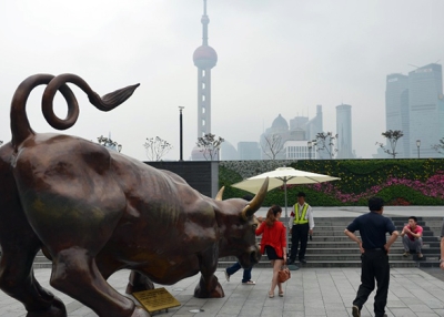Visitors have photos taken with a replica of the famous Wall Street bronze bull on the Bund in Shanghai on June 13, 2013. (Peter Parks/AFP/Getty Images)
