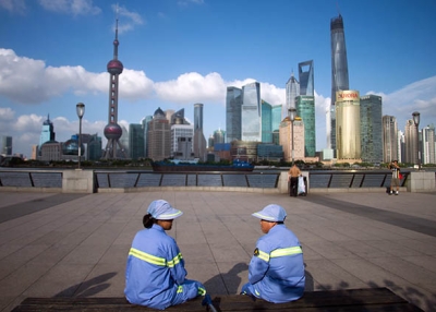 Two cleaners have a rest on a bench at the Bund before the Huangpu River and the skyline of the Lujiazui Financial District in Shanghai. (Johannes Eisele/AFP/Getty)