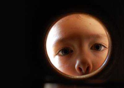 A child looks through a small window or opening. (Caritas5/Flickr)