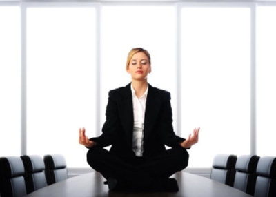 Woman meditating on table of meeting room