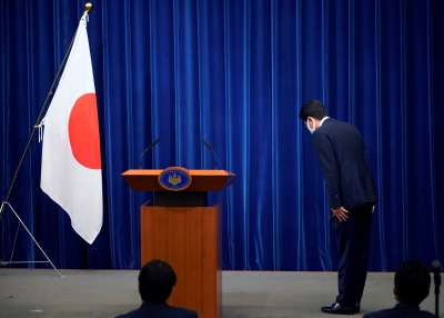 Japanese Prime Minister Shinzo Abe bows to the national flag at the start of a press conference announcing his resignation due to health concerns