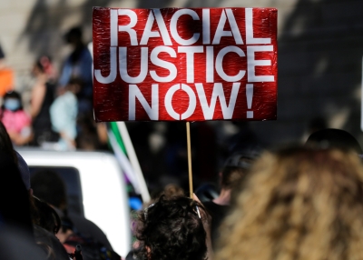 A protestor holds a "Racial Justice Now" sign