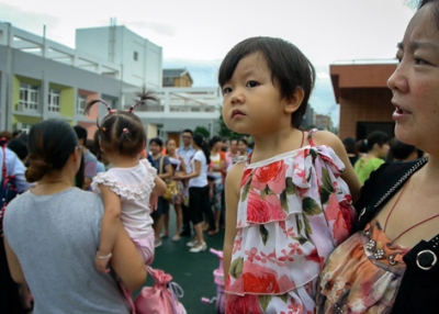 Fu Guangjun holds her daughter Jiang Yutong, 2, on the first day of preschool classes in New Beichuan. Film still from 'The Reborn of Beichuan.'
