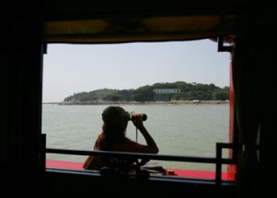A Chinese tourist looks at the Kinmen, the front line island between Taiwan and China's Xiamen, with her telescope on a Chinese pleasure boat in Jinmen, Taiwan, in 2006. (Getty Images)