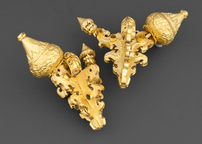 Large ear ornaments with stylized fruit and bud motif.