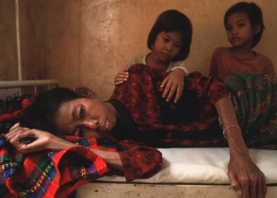 Two daughters look at their mother who is dying from HIV/AIDS in Cambodia. (Photo by Masaru Goto / World Bank)