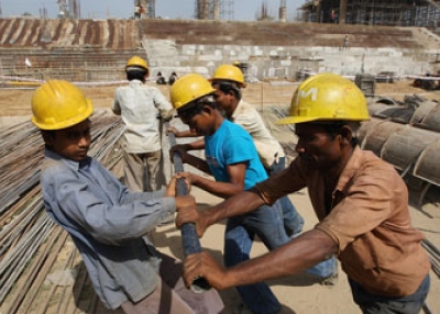 Indian laborers carry building materials as construction work goes in full swing at Thyagaraj Stadium in New Delhi in 2008.