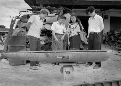 A family weighs an American cluster bomb casing at a scrap dealer in Phonsavanh, Laos (Jerry Redfern)