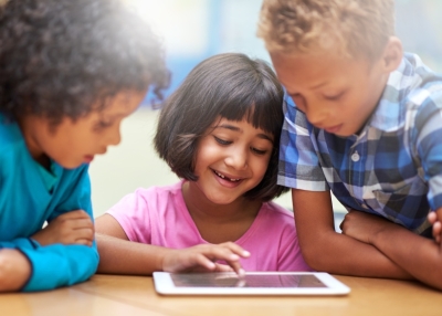 Children look at a tablet together.