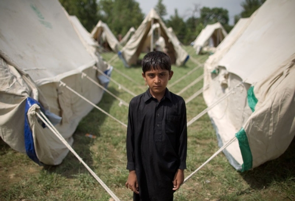 A boy who gave his name as Jeeshan stands outside his tent in a camp set up by the Pakistani army inside a college on the outskirts of Nowshera on August 2, 2010. (Behrouz Mehri/AFP/Getty Images)