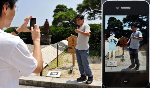 In a composite of photos taken on Aug. 21, 2010 a man (C) in Atami poses next to a tiny B & W panel that becomes an animated image of a girl when the image is processed through an iPhone application (R). (Kazuhiro Nogi/AFP/Getty Images) 
