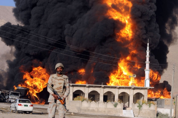 A Pakistani paramilitary soldier stands guard in front of burning NATO supplies oil tankers following a gunmen attack in Quetta on October 6, 2010. (Banaras Khan/AFP/Getty Images) 
