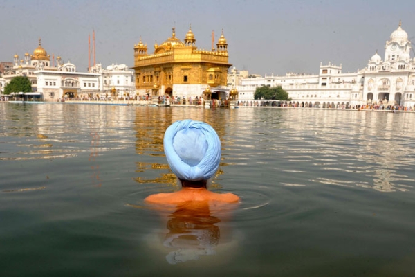 An Indian Sikh devotee takes a dip in the holy sarover (water tank) at the Sikh Shrine Golden Temple in Amritsar on November 5, 2010.