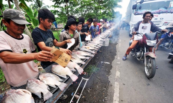 Motorists pass by thousands of residents grilling fish along a highway in Buluan town, Maguindanao province