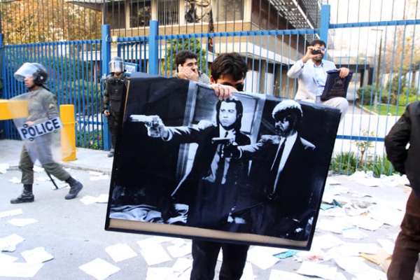 A man holds a poster featuring American actors John Travolta and Samuel L. Jackson in a scene from the film 'Pulp Fiction' following a break in at the British Embassy on November 29, 2011 in Tehran, Iran. (FarsNews/Getty Images)