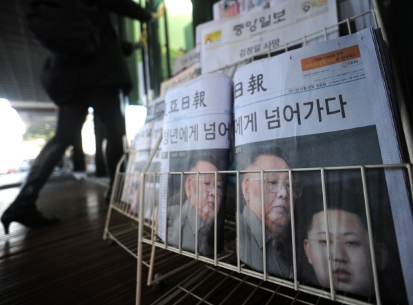 Residents walk past newspapers showing the late North Korean leader Kim Jong-Il and his son Kim Jong-Un outside a convenience store in Seoul on December 20, 2011. (Sam Yeh/AFP/Getty Images)