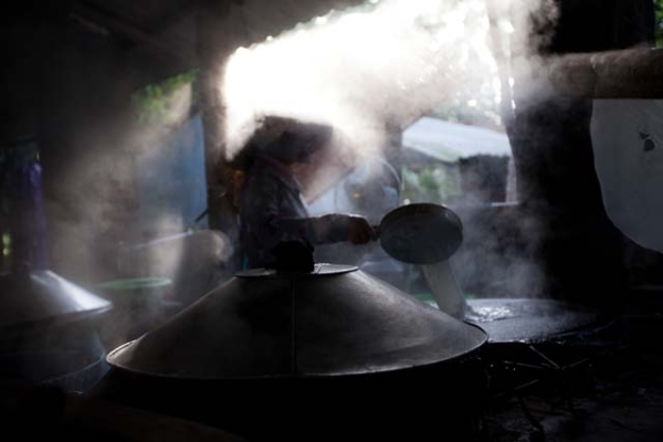 A cook shrouded in steam inside a rice noodle factory. (Hélène Franchineau)