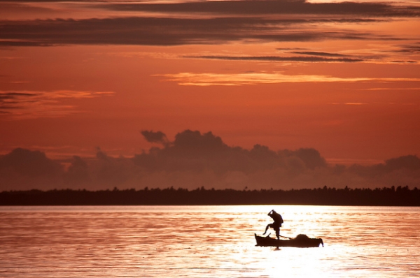 A man abandons his boat and steps into the water in Fiji during sunrise on April 5, 2012. (kyle post/Flickr)