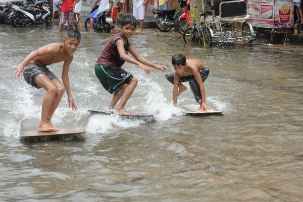 Children use plywood to surf in a flooded street in the town of Navotas in suburban Manila on August 2, 2012. (Jay Directo/AFP/GettyImages) 