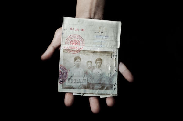 Sonny Vaahn, 25, holds his family members' refugee ID card, given upon initial entry into a refugee camp along the Thai-Cambodian border. (Pete Pin)