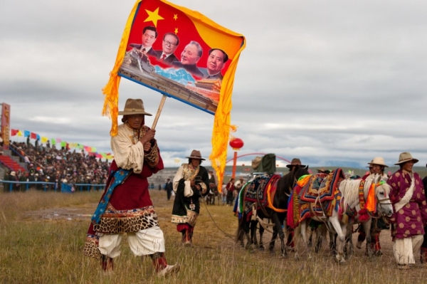 Tibetan cowboy carries a banner which would surely please the government officials in attendance. (Michael Yamashita)