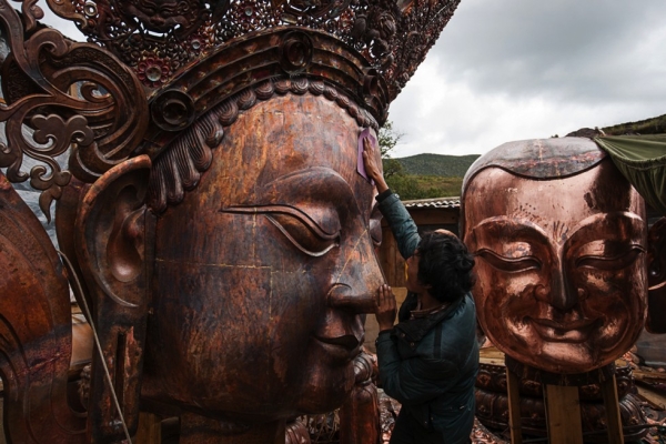 A craftsman polishes the nose of a gigantic copper Buddha at a monastery workshop in Shangri-La. (Michael Yamashita)