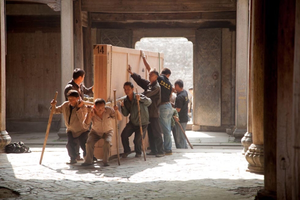 Ten local villagers work with employees of Huaxie International Fine Art to load crates of photographs into Guanyu Tang ancestral hall in Pingshan Village in preparation for the Coal+Ice exhibition. (Leah Thompson)