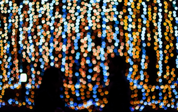 Two people pause in front of twinkling Christmas lights in Tokyo, Japan on Decmeber 11, 2012. (lestaylorphoto/Flickr)