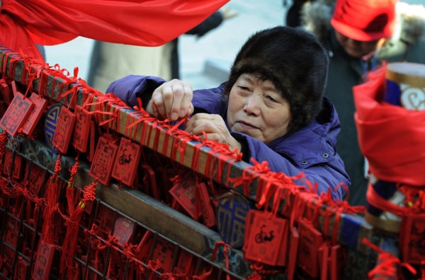 An elderly Chinese woman attaches a blessing tablet with her new year wishes at the Dongyue Temple in Beijing on January 23, 2012. (Mark Ralston /AFP/Getty Images)