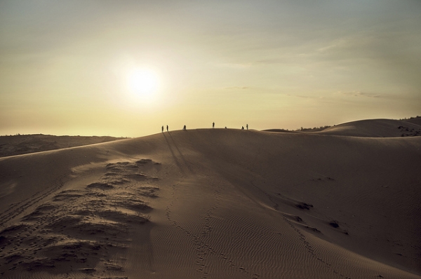 A group of people are silhouetted against the blazing sun on sand dunes in Mui Ne, Vietnam on January 30, 2013. (arthur.l.I/Flickr)