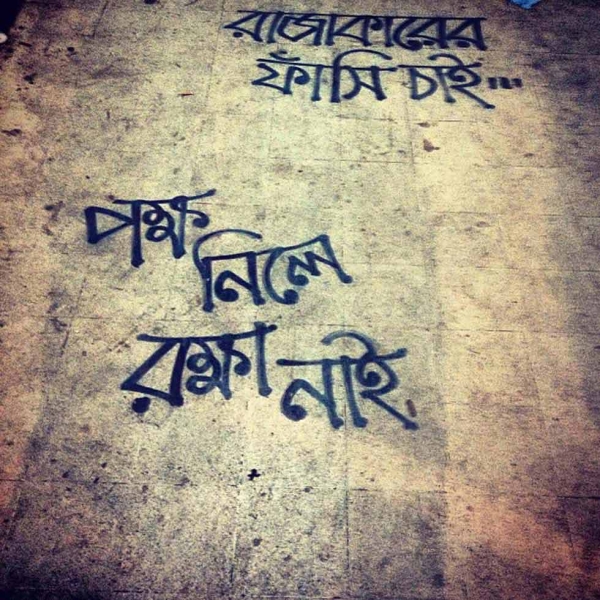 Bangla graffiti on the pavement reads: Hang the "rajakar." No protection for those who pick sides. (Naorose Bin Ali)