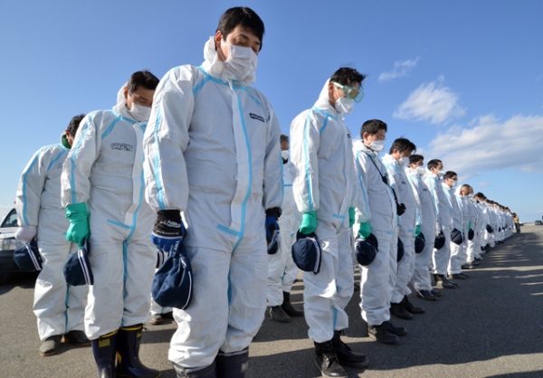 Police officers in radiation protection suits bow their heads to offer prayers in silence for tsunami victims in Namie, near the stricken TEPCO's Fukushima Dai-ichi nuclear plant in Fukushima prefecture commemorating the second anniversary of the diasater on March 11, 2013. (Yoshikazu Tsuno/AFP/Getty Images)